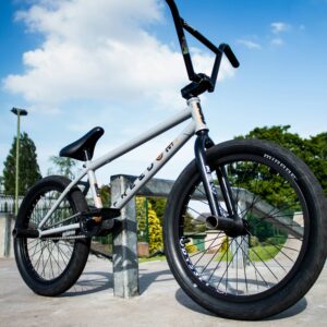 Silver BMX bike on concrete with blue sky background.