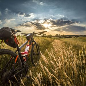 Bicycle wheel splashing through water at sunset, with vibrant orange and blue sky reflecting on the wet surface.