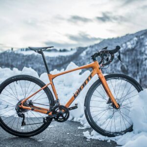 The AI preSleek orange road bike parked on a snowy mountain pass.the AI post
